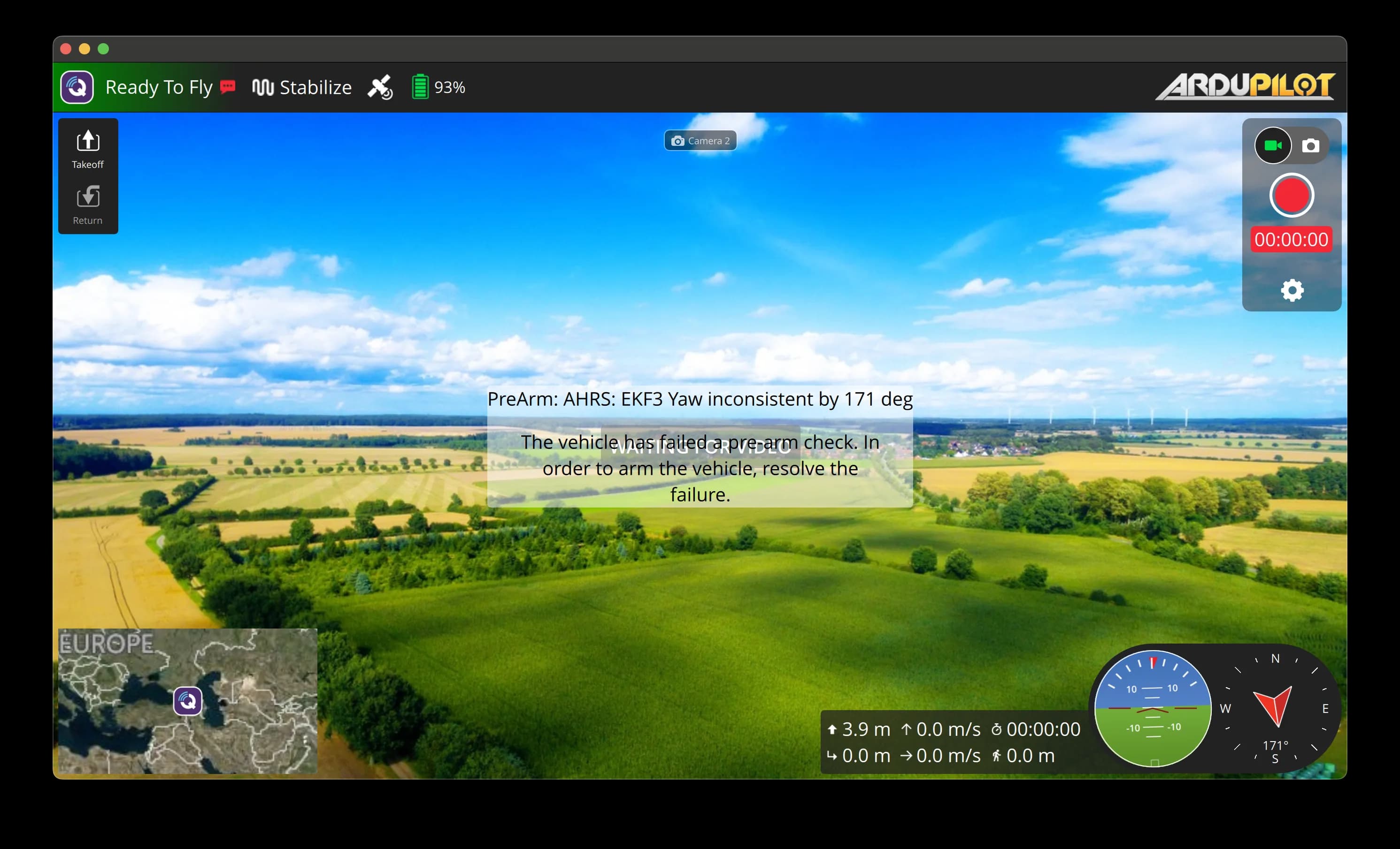QGroundControl flight view streaming live drone video with a camera switch button at the top center, telemetry and attitude indicators overlaid.